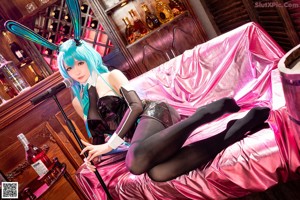 A woman sitting on a pink couch in a room.