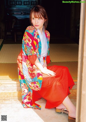 A woman in a colorful kimono standing on a beach.