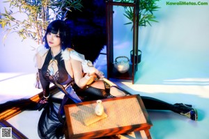 A woman sitting on a chair in front of a bamboo tree.