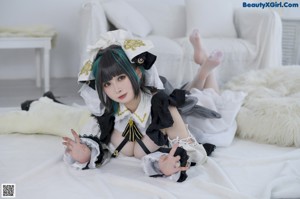 A woman in a black and white dress sitting on a bed.