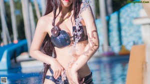 A woman in a black bikini standing in a pool.