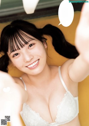 A woman in a white bra and blue shorts posing for a magazine.