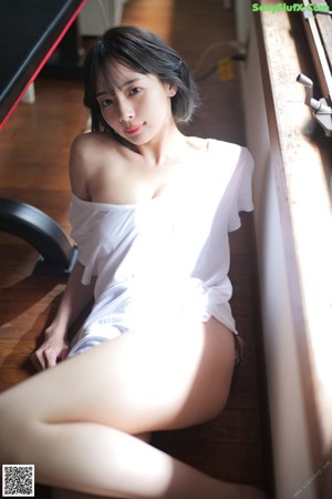 A woman in a white shirt is sitting on the floor.
