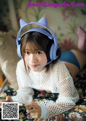 A woman in a blue bikini and headphones laying on a bed.