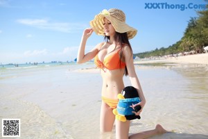 A woman in an orange bikini sitting on a boat.