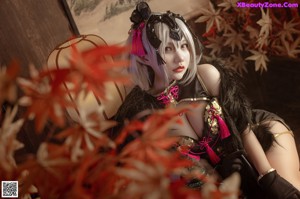 A woman in a black and pink outfit sitting on a wooden floor.
