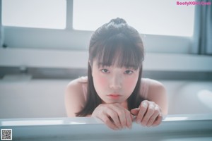 A doll sitting in a bathtub with water on her legs.