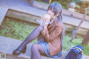 A woman in a school uniform sitting on a stone ledge.