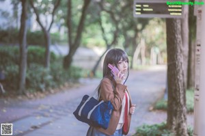 A woman in a school uniform is walking down a sidewalk.