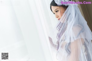 A woman in a white lingerie leaning against a window.