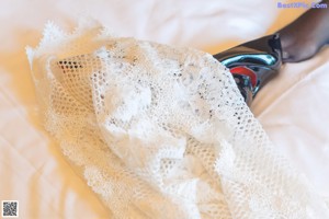 A woman in a white lingerie and black stockings sitting on a bed.