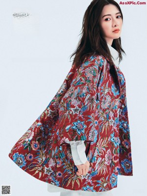 A woman in a floral dress holding a pink purse.