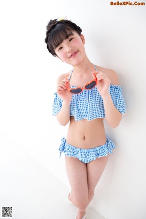 A young woman in a blue and white checkered bikini and sunglasses.