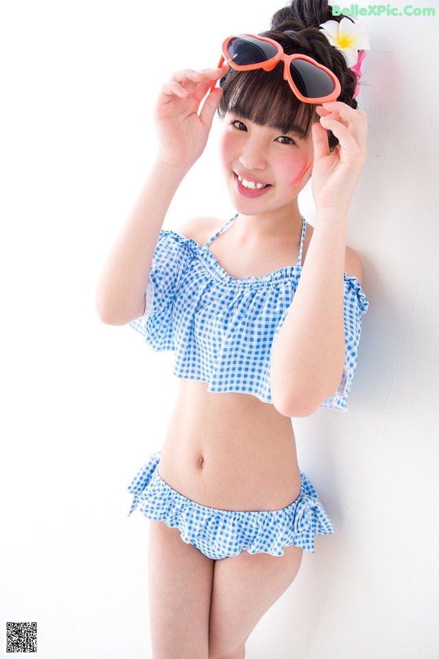 A young woman in a blue and white checkered bikini and sunglasses.