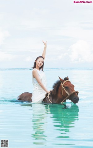 A woman leaning on the edge of a swimming pool.