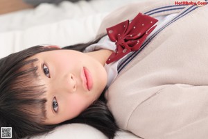 A woman in a school uniform sitting on a bed.