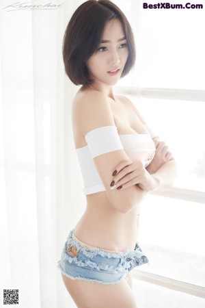 A woman in a white top and blue shorts posing for a picture.