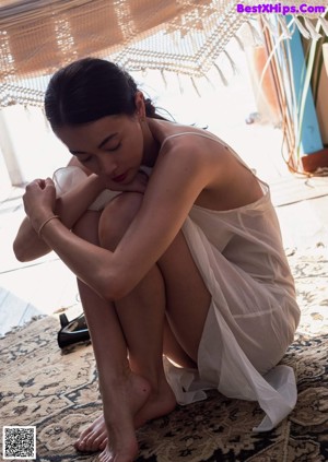 A woman sitting on the floor with her head in her hands.