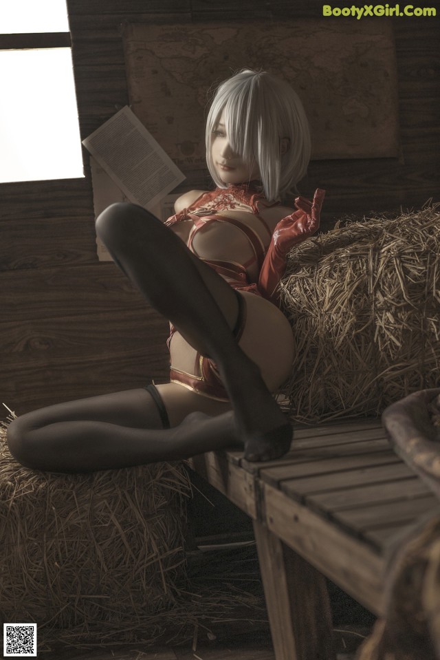 A woman sitting on top of a pile of hay.