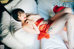 A woman in a red dress sitting on a bed.