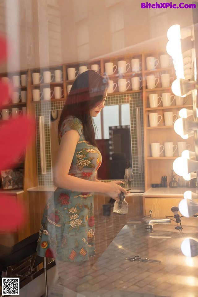 A woman standing in front of a mirror in a hair salon.