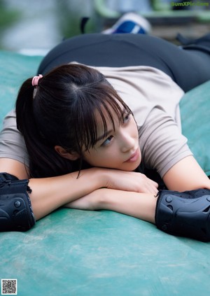 A woman in a beige shirt and black leggings doing a yoga pose.